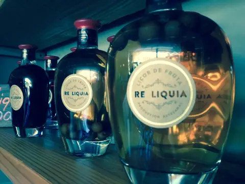 Bottles of RE Liquia artisanal fruit liqueur on a wooden shelf at Bodegas RE, Casablanca Valley