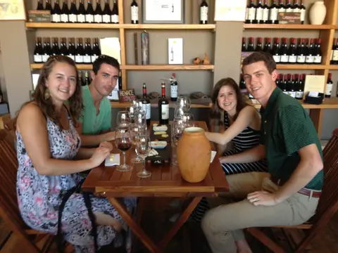 Four guests around a wooden table with a clay jar and a slate of cheese in the Bodegas RE shop
