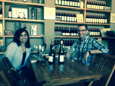 Couple seated with two bottles of white wine in the Bodegas RE tasting room, shelves of wine behind