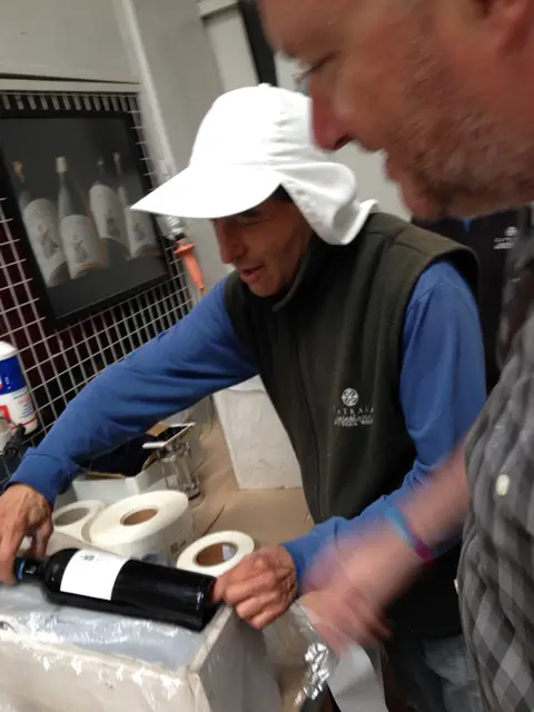 Winery worker in a Catrala fleece applying labels to bottles by hand