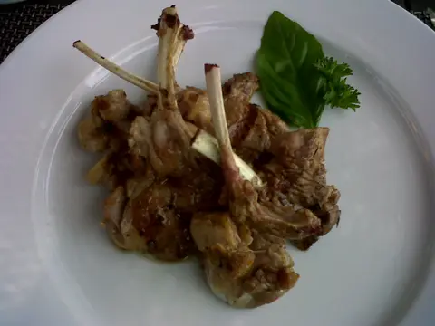 Grilled lamb chops served on a white plate with basil and parsley at a winery restaurant