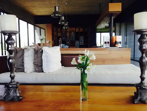 Modern winery tasting room with a low sofa, candlesticks and a wooden bar lined with bottles