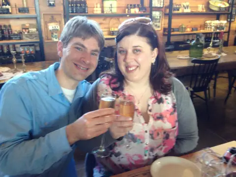 Couple raising sparkling wine flutes in a winery tasting room