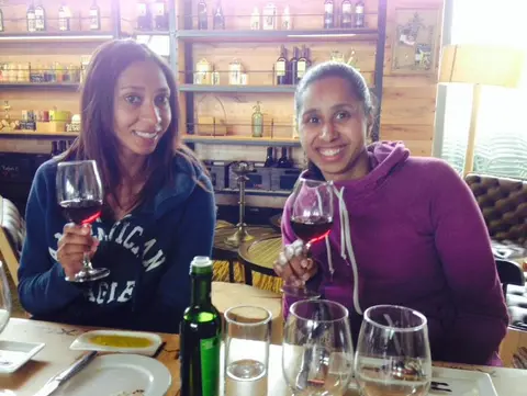 Two guests holding glasses of red wine at a tasting room table