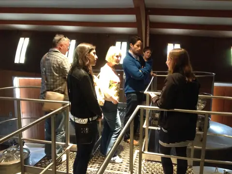 Guide talking to a family group on a walkway above stainless steel fermentation tanks