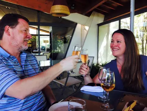 Couple toasting with glasses of sparkling wine at a winery restaurant table