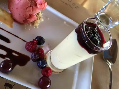 Panna cotta with berry compote, sorbet and fresh berries on a white plate at a winery restaurant