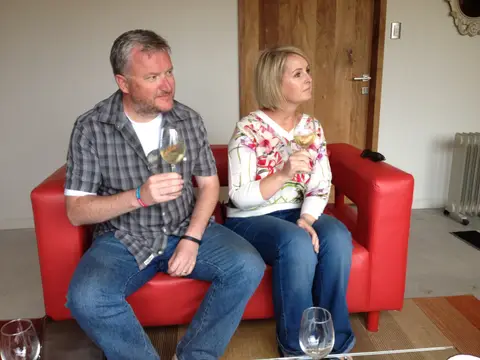 Couple sitting with glasses of white wine on a red leather sofa in a winery lounge