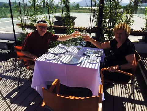 Couple toasting with white wine at a set table on a shaded winery terrace